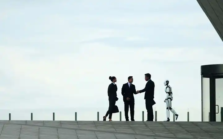 Business partners shaking hands on a rooftop beside a humanoid robot