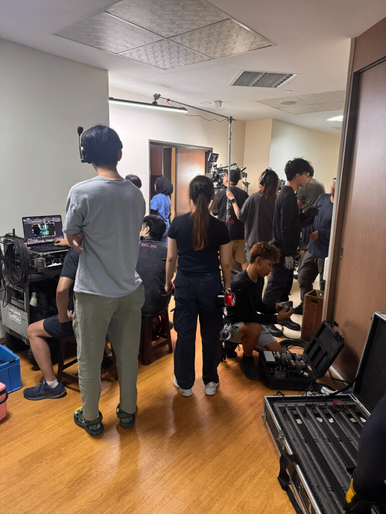 Crew with lights, a boom and a camera filming a nurse scene in a hospital corridor