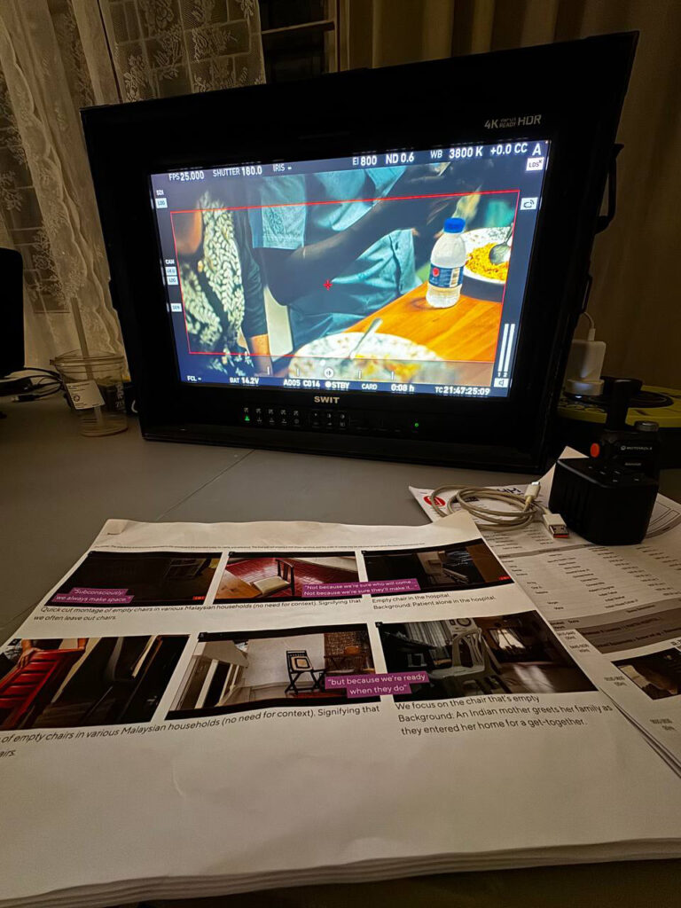 Field monitor showing a dinner scene, with the printed storyboard on the table in front of it