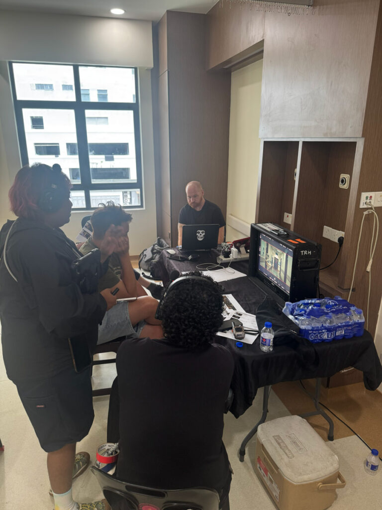 Crew watching a monitor at a table set up inside a hospital room
